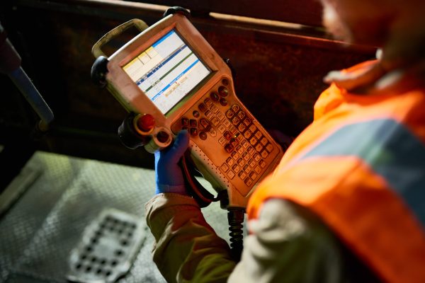 Close up of unrecognizable worker holding control panel of power unit, reading info on screen